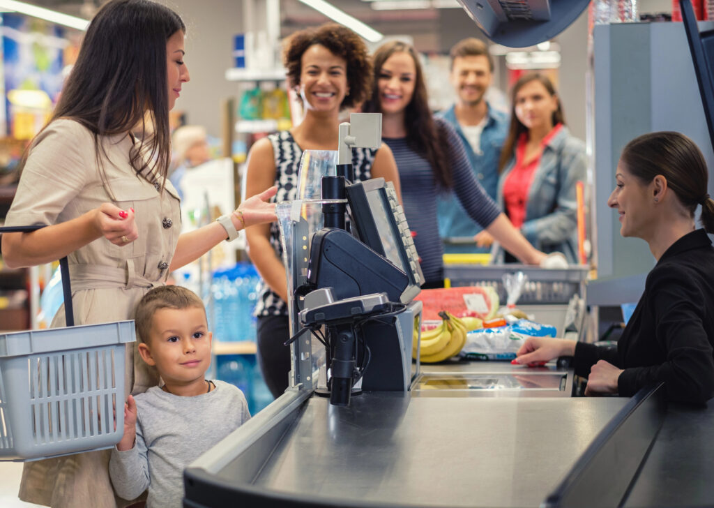 Woman is paying for groceries with a child beside her