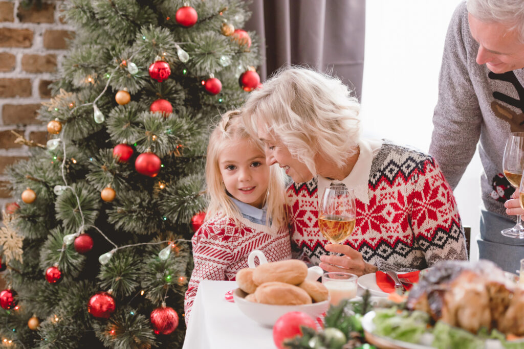 Girl hugs grandma near Christmas tree