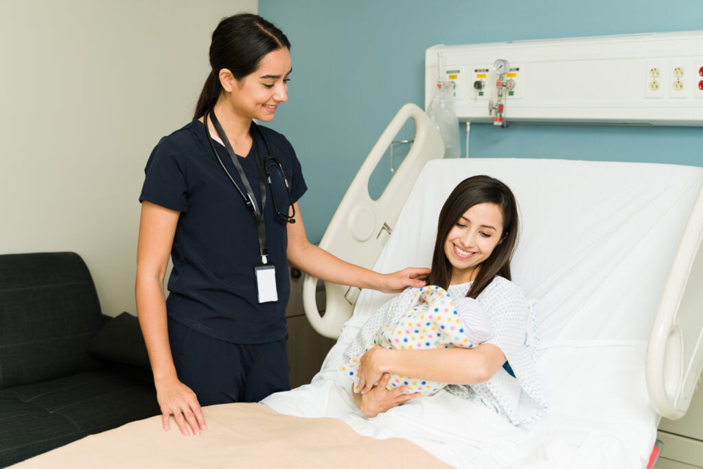 Mom is in hospital with newborn as nurse comforts her