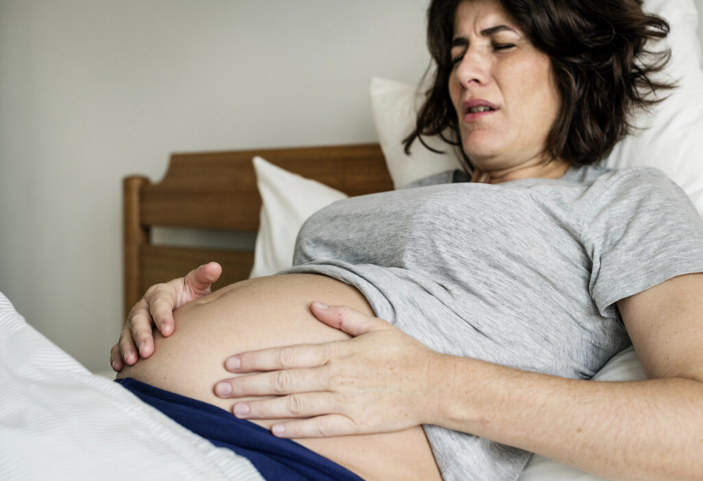 Woman holds abdomen while grimacing in labor