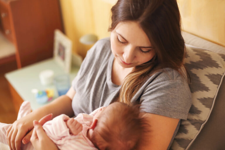 Young mother holding her newborn child. Mom nursing baby. Family