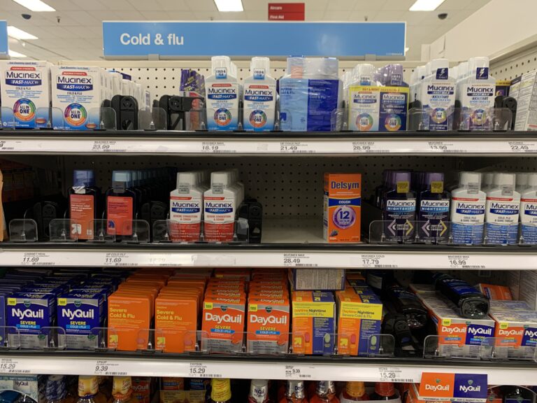 A retail store pharmacy shelf displaying various cold and flu medications, including Mucinex, NyQuil, DayQuil, and Delsym at Cold and Flu section - California, USA - January 29, 2025