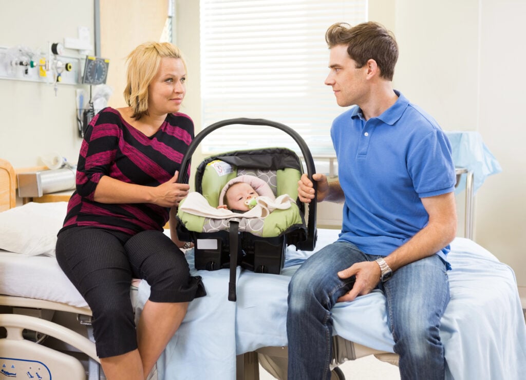 Couple With Baby Looking At Each Other On Hospital Bed