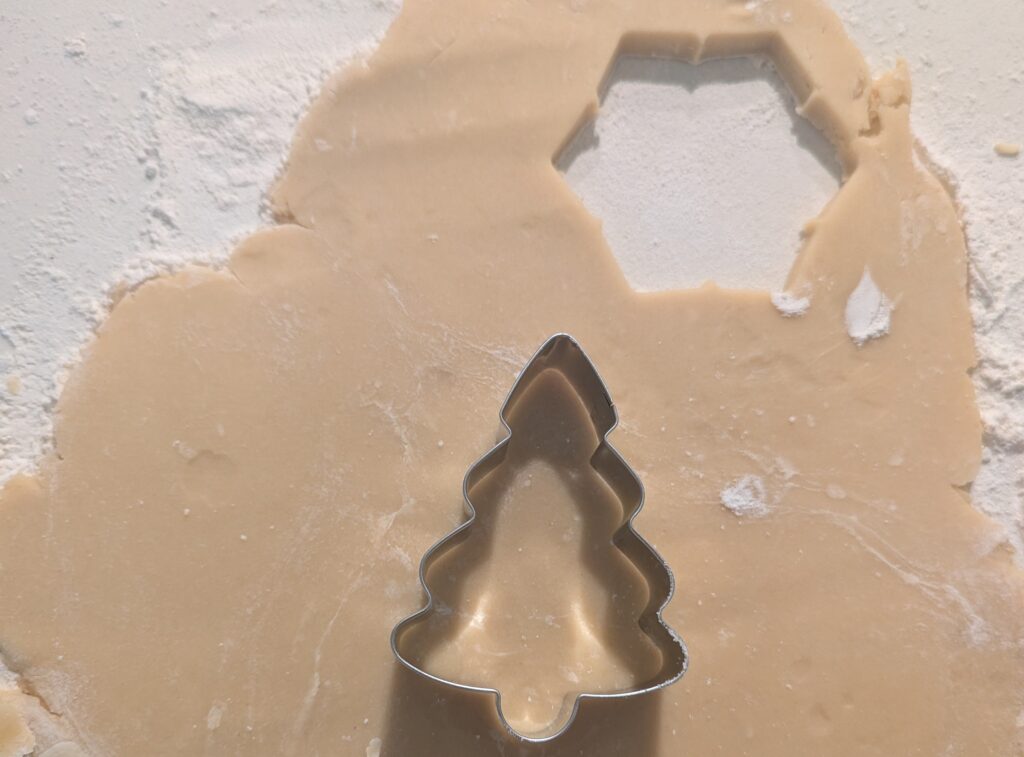 sugar cookie dough rolled out with Christmas tree cookie cutter