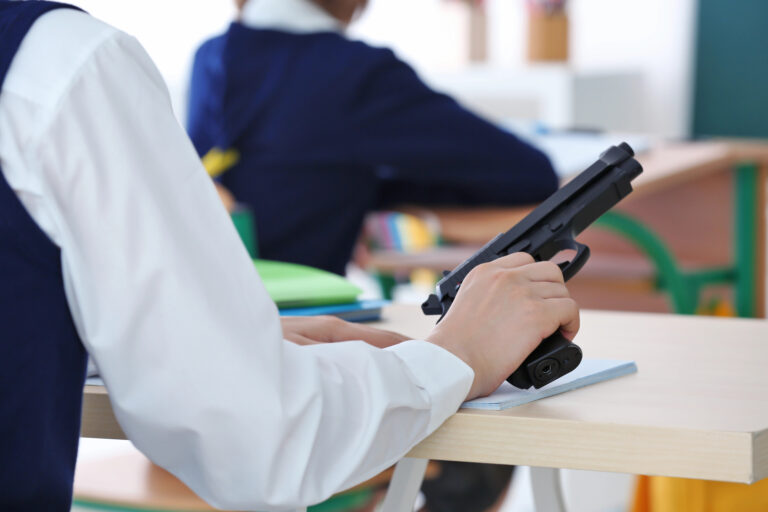 Schoolboy holding gun in classroom