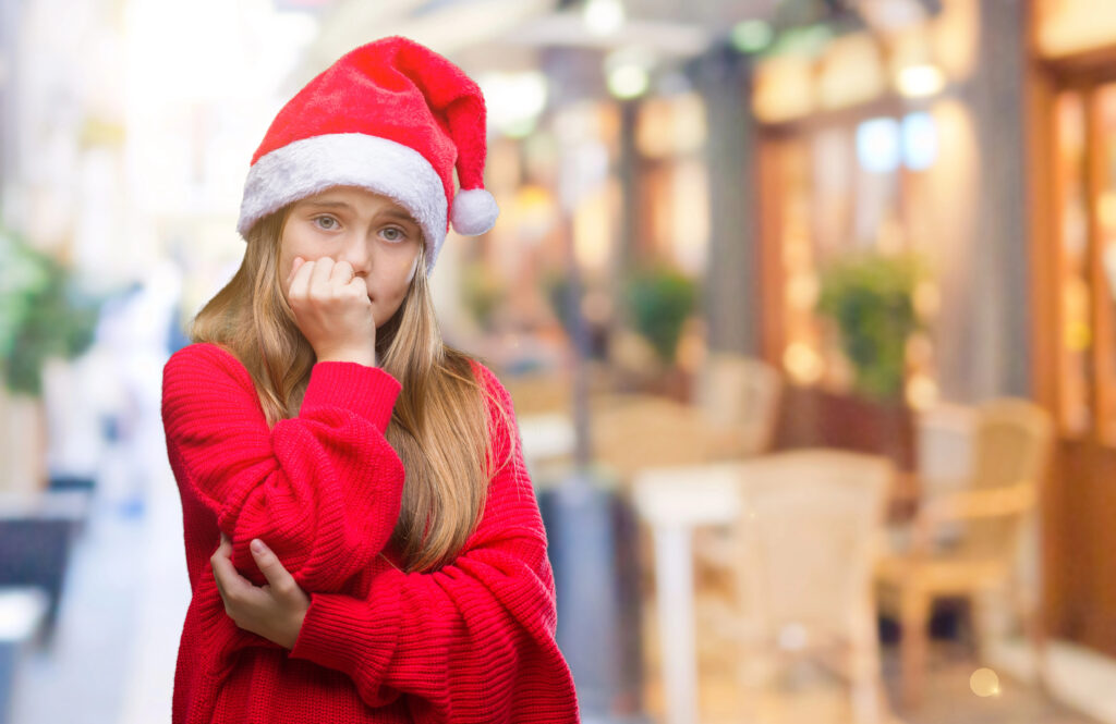 A shy child is wearing a santa hat but is anxious