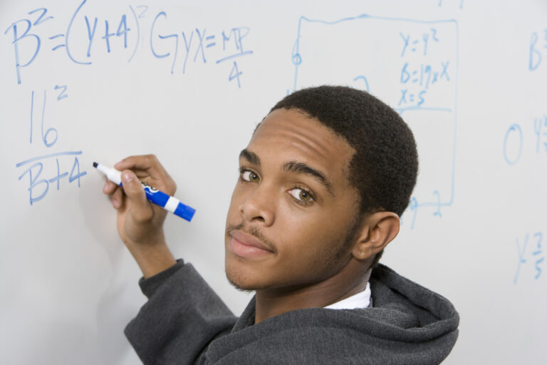teen writes math on the markerboard